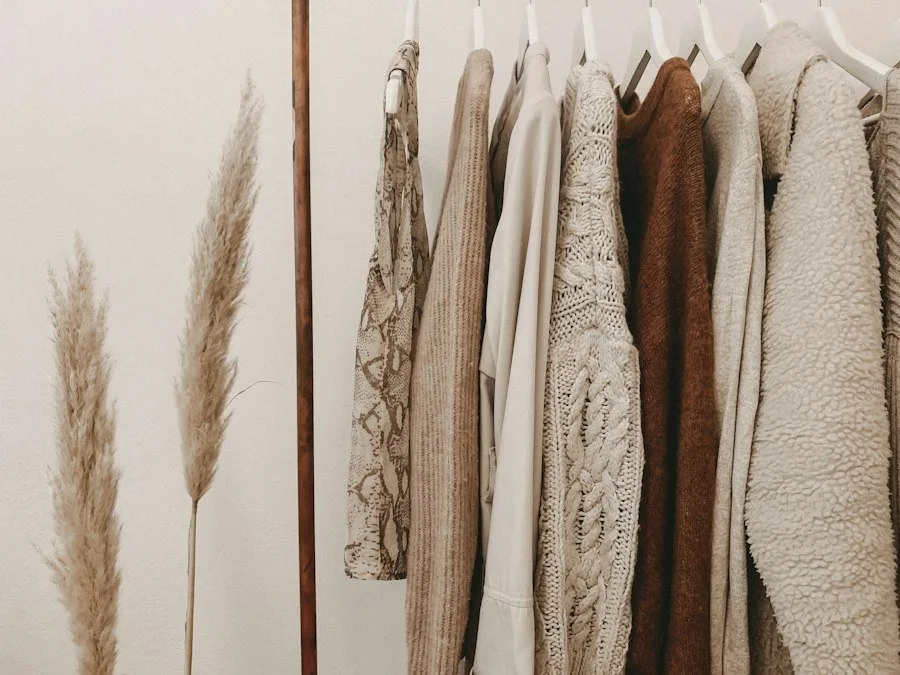 Rail of cream and brown knitwear next to dried pampas grass