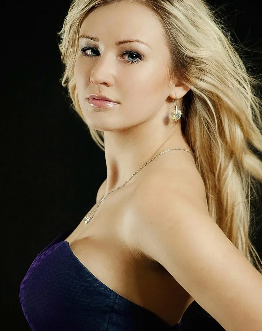 Blonde woman in a navy strapless top looking back over her shoulder