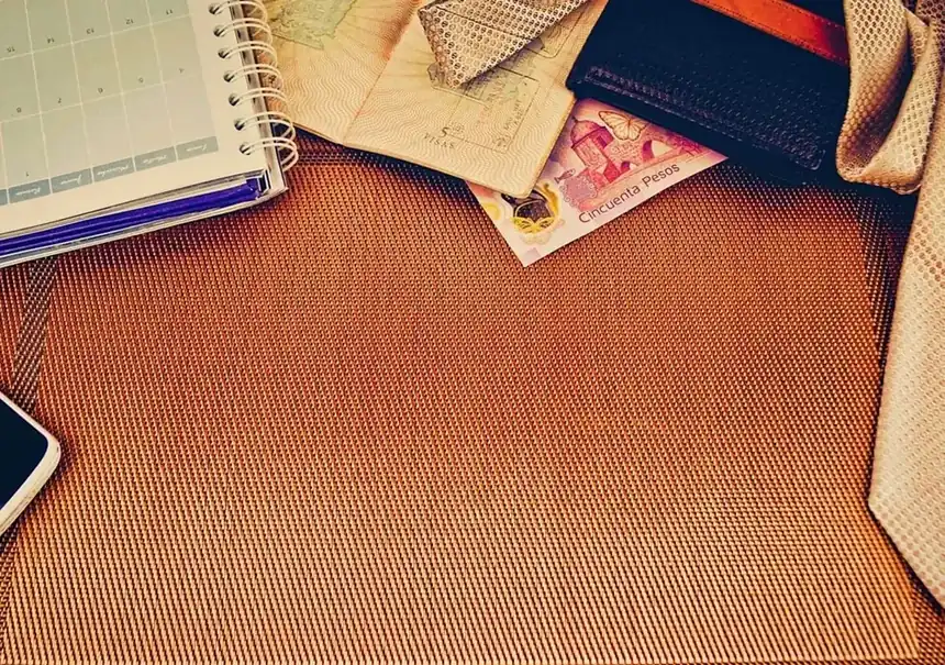Pocket planner, phone and folded scarves laid out on a woven tabletop