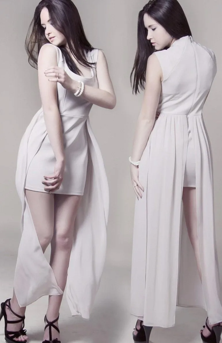 Two women in pale, flowing evening dresses and strappy heels against a soft grey backdrop